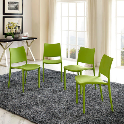 Four lime-green molded plastic dining chairs with metal legs, arranged on a gray shag rug in a bright modern room.