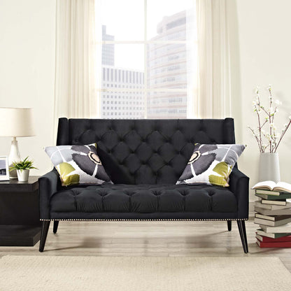 Black tufted velvet loveseat with nailhead trim and angled legs, paired with gray-green abstract pillows in a bright living room.