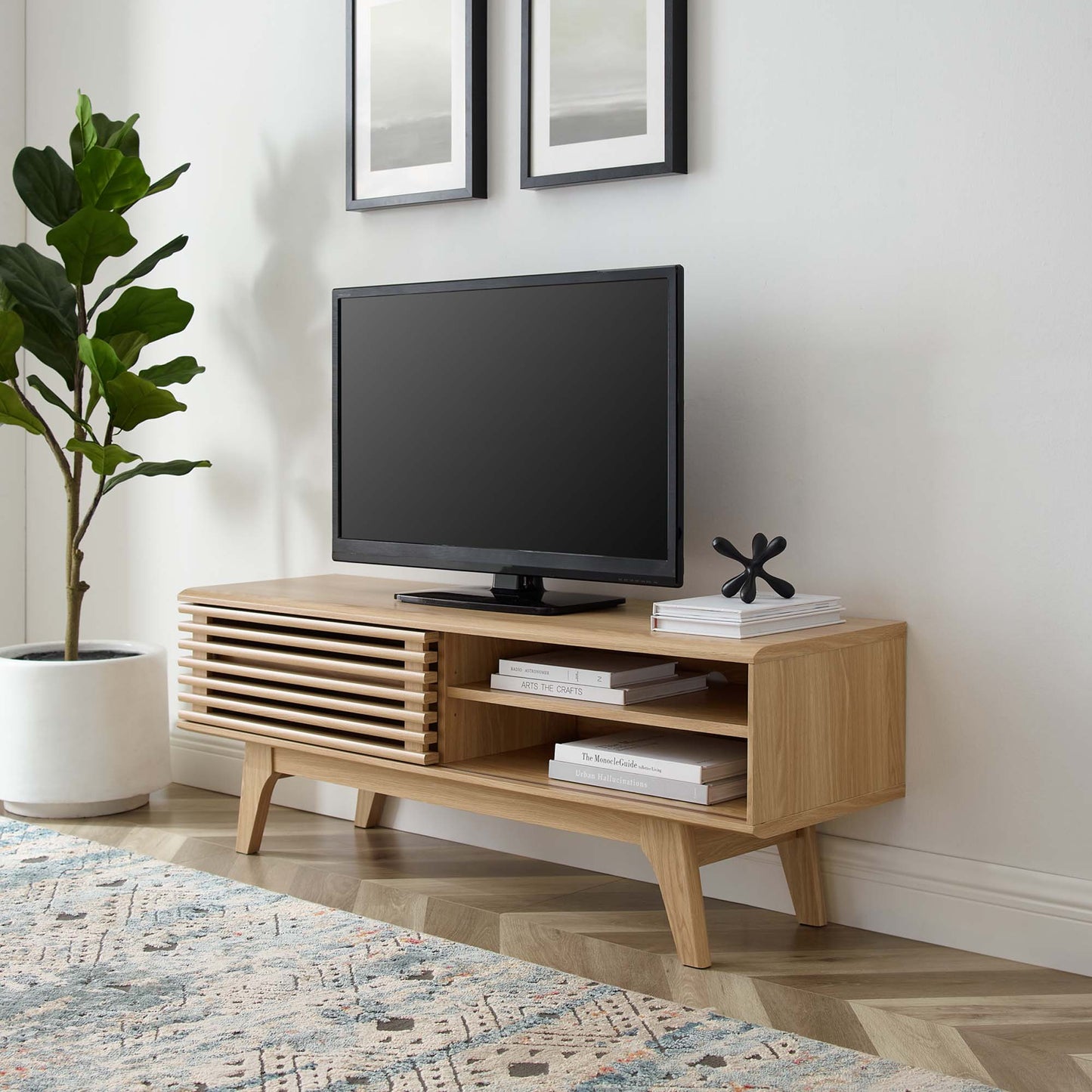 Brown oak TV stand with angled legs, slatted drawer and open shelves; TV, books and decor.