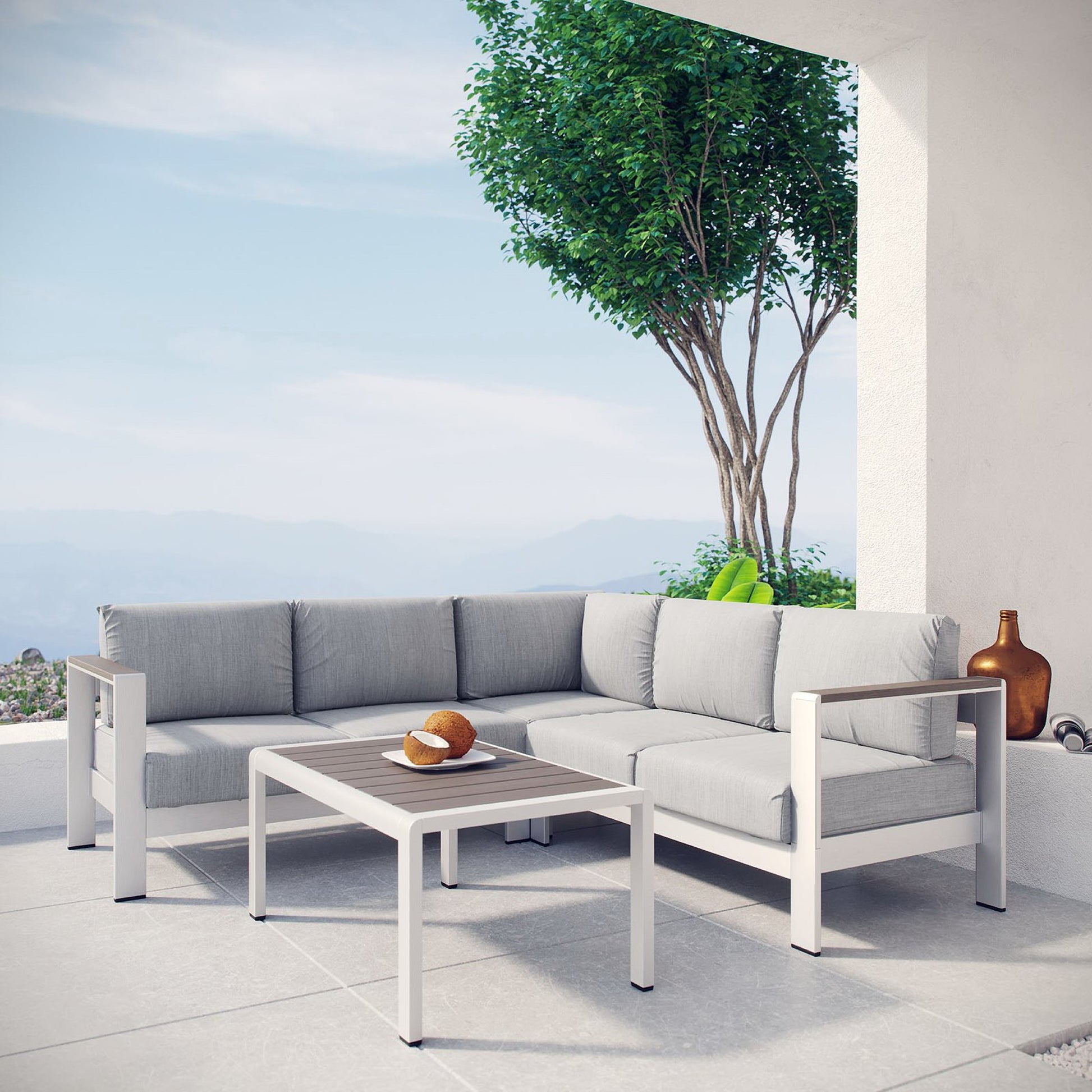 Outdoor modular sofa set with gray cushions and white frame, matching coffee table on a terrace with sea view.