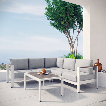 Outdoor modular sofa set with gray cushions and white frame, matching coffee table on a terrace with sea view.
