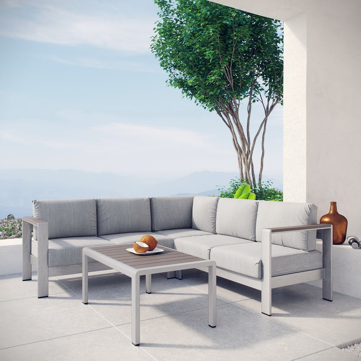 Slate gray aluminum-frame outdoor sectional with light gray cushions and a matching square coffee table on a sunny patio.