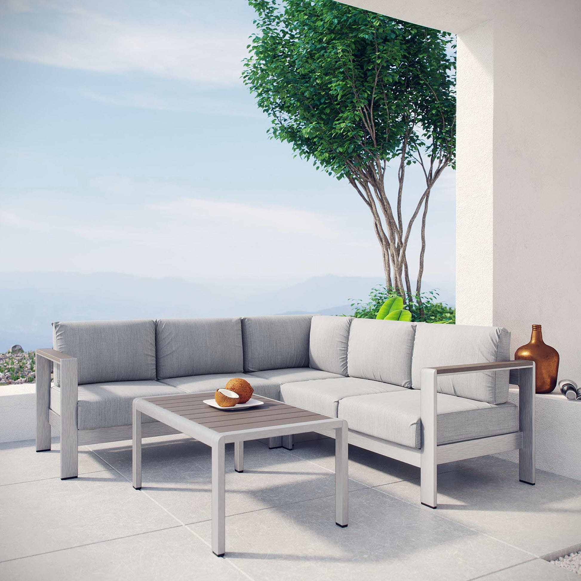 Slate gray aluminum-frame outdoor sectional with light gray cushions and a matching square coffee table on a sunny patio.