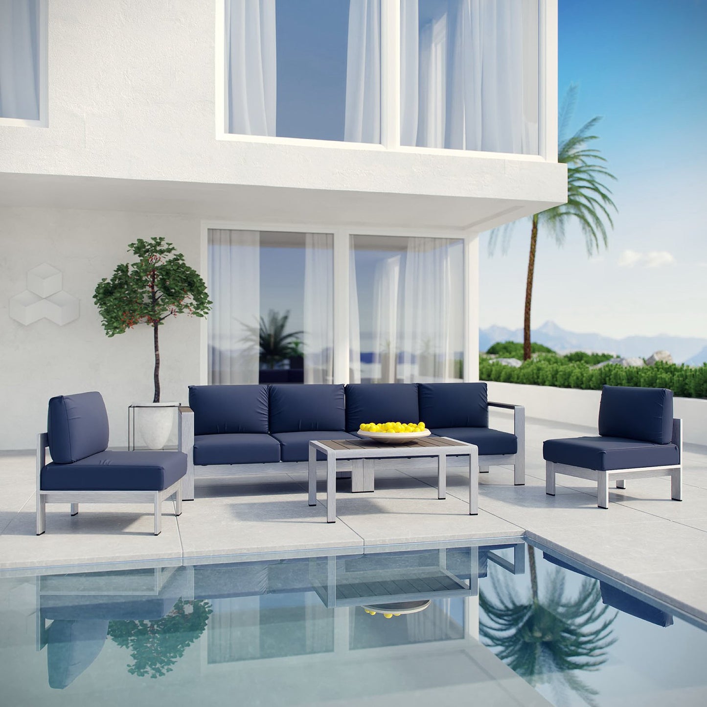 Modern outdoor lounge set with navy cushions on grey frames, coffee table, poolside patio with palms.