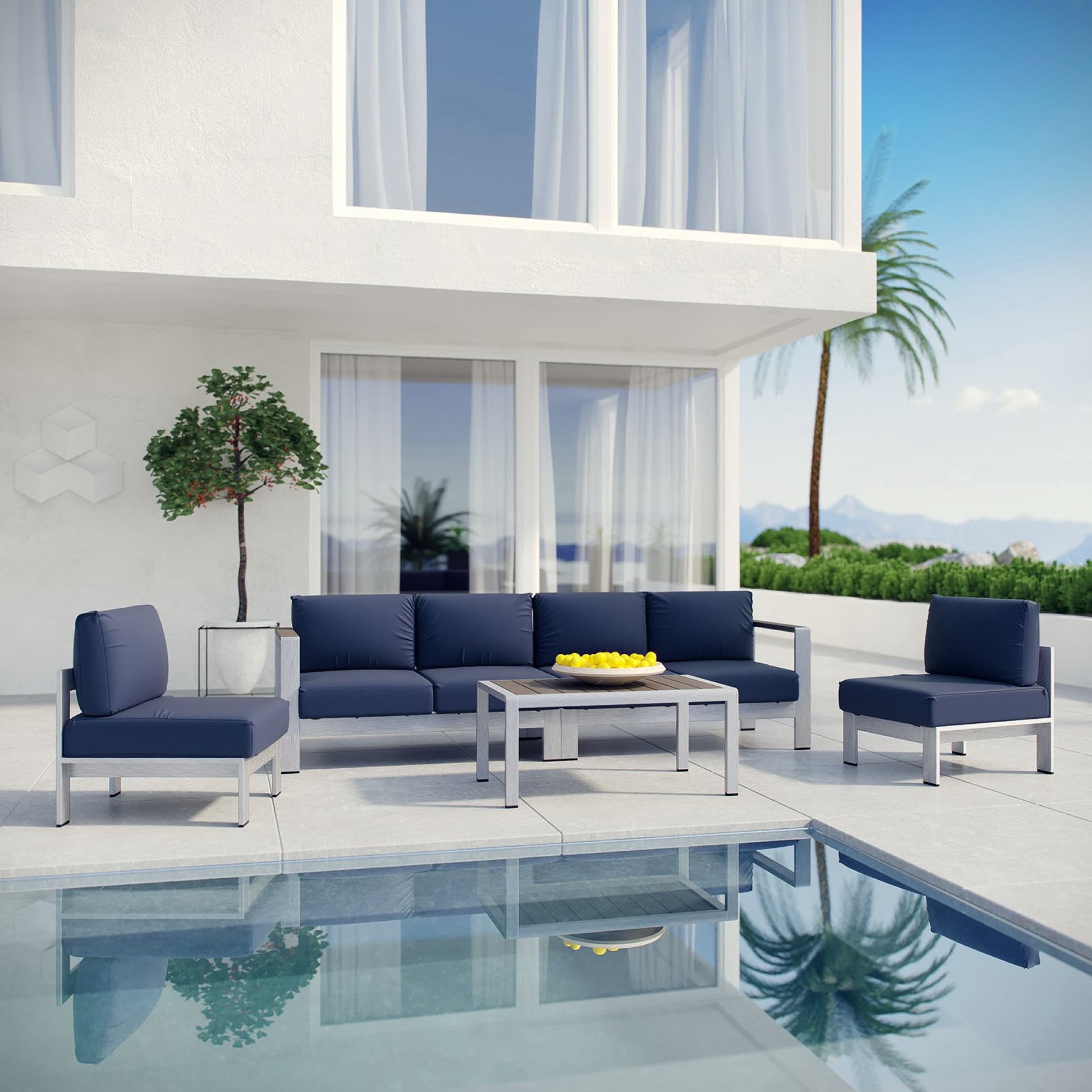 Modern outdoor lounge set with navy cushions on grey frames, coffee table, poolside patio with palms.