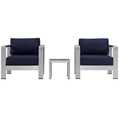 Pair of modern silver metal-frame armchairs & navy cushions with a small square side table.