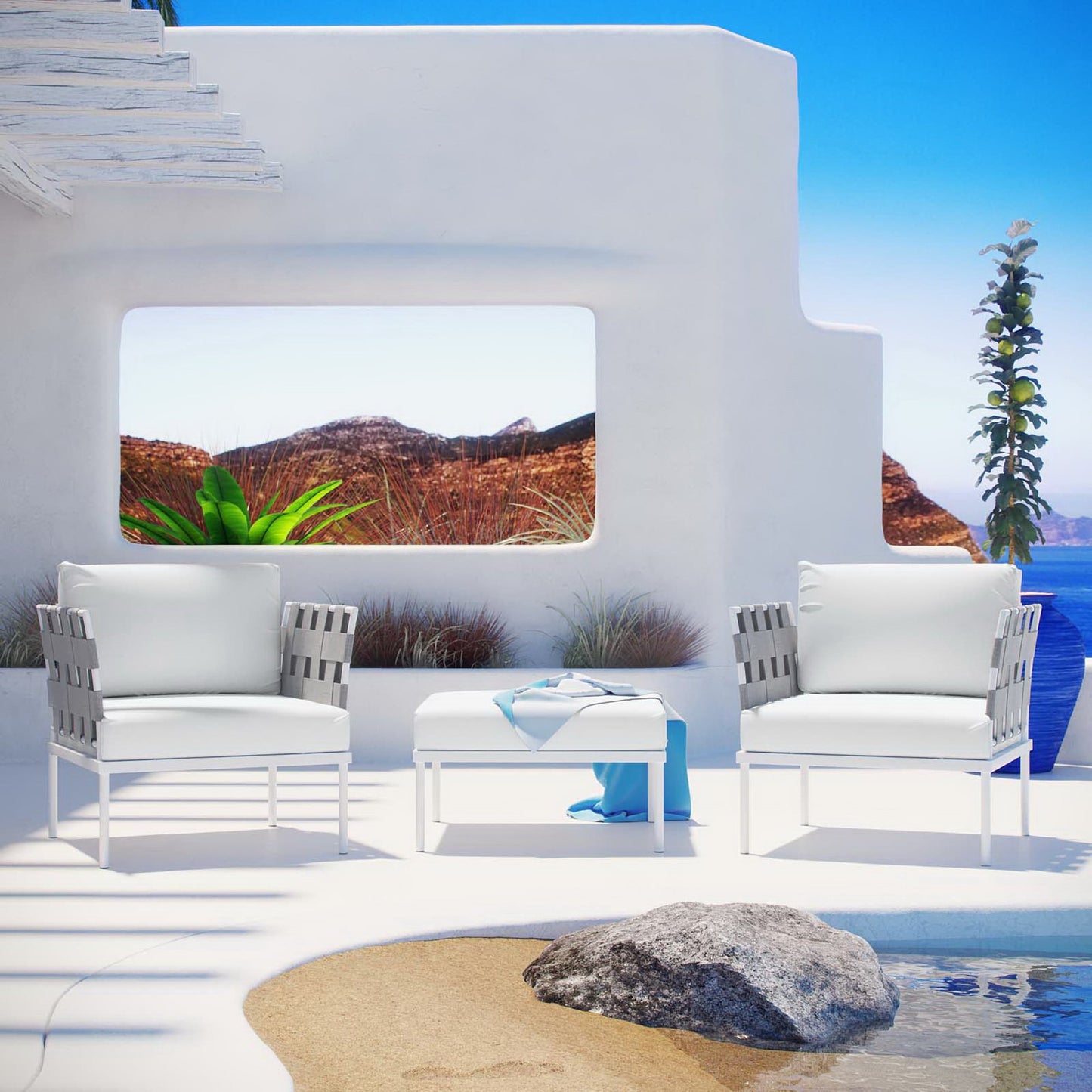 White outdoor aluminum 3-piece sectional sofa set with cushioned seating and a small white coffee table on a sunlit coastal terrace.