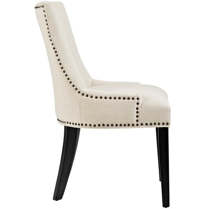 Beige fabric dining chair with curved back, dark wood legs, and nailhead trim along edges.
