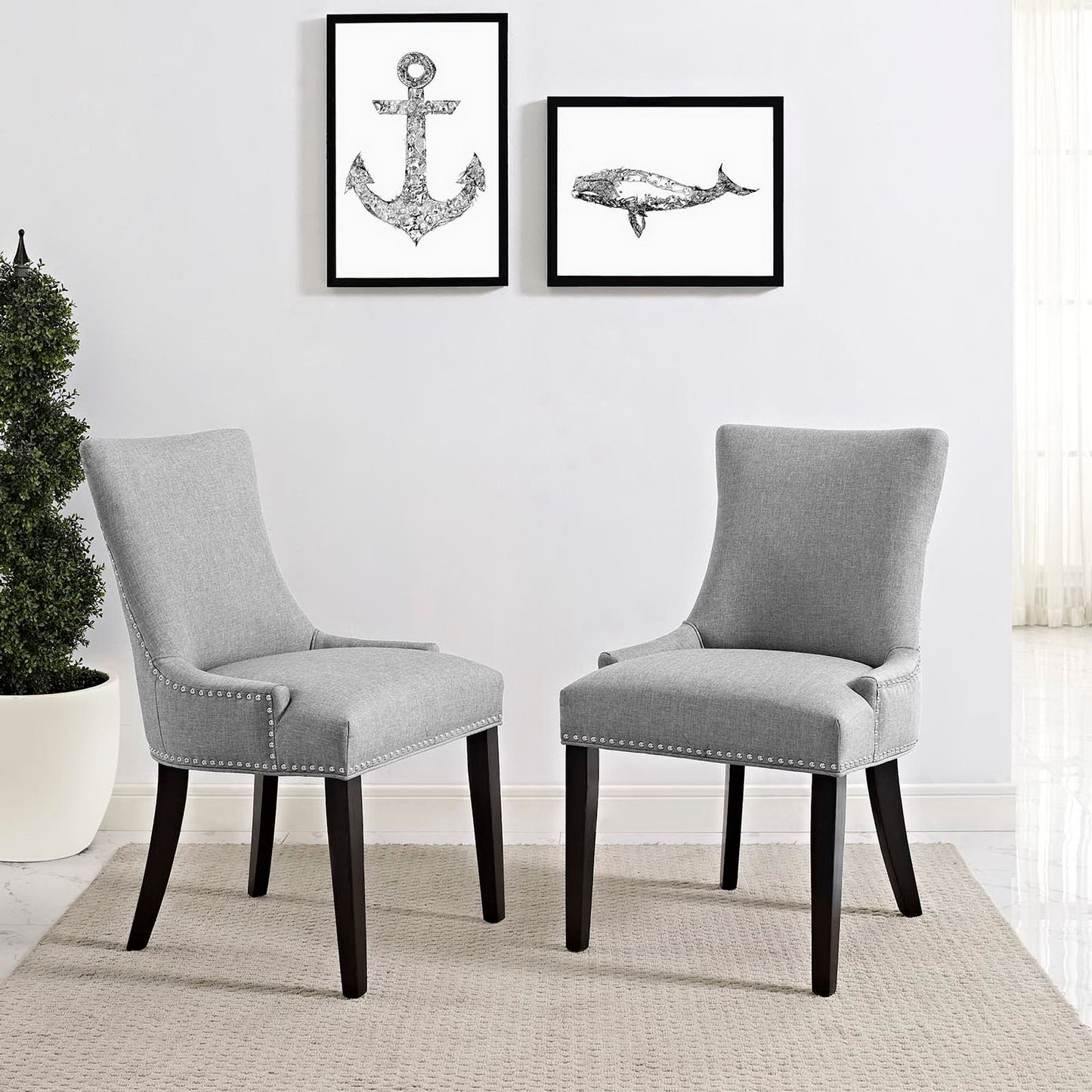 Pair of light gray upholstered armless dining chairs with dark wood legs and nailhead trim.