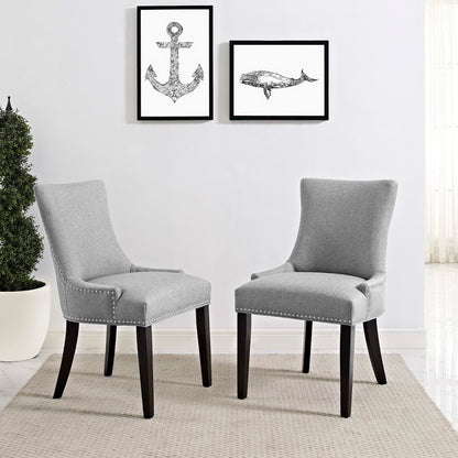 Pair of light gray upholstered armless dining chairs with dark wood legs and nailhead trim.
