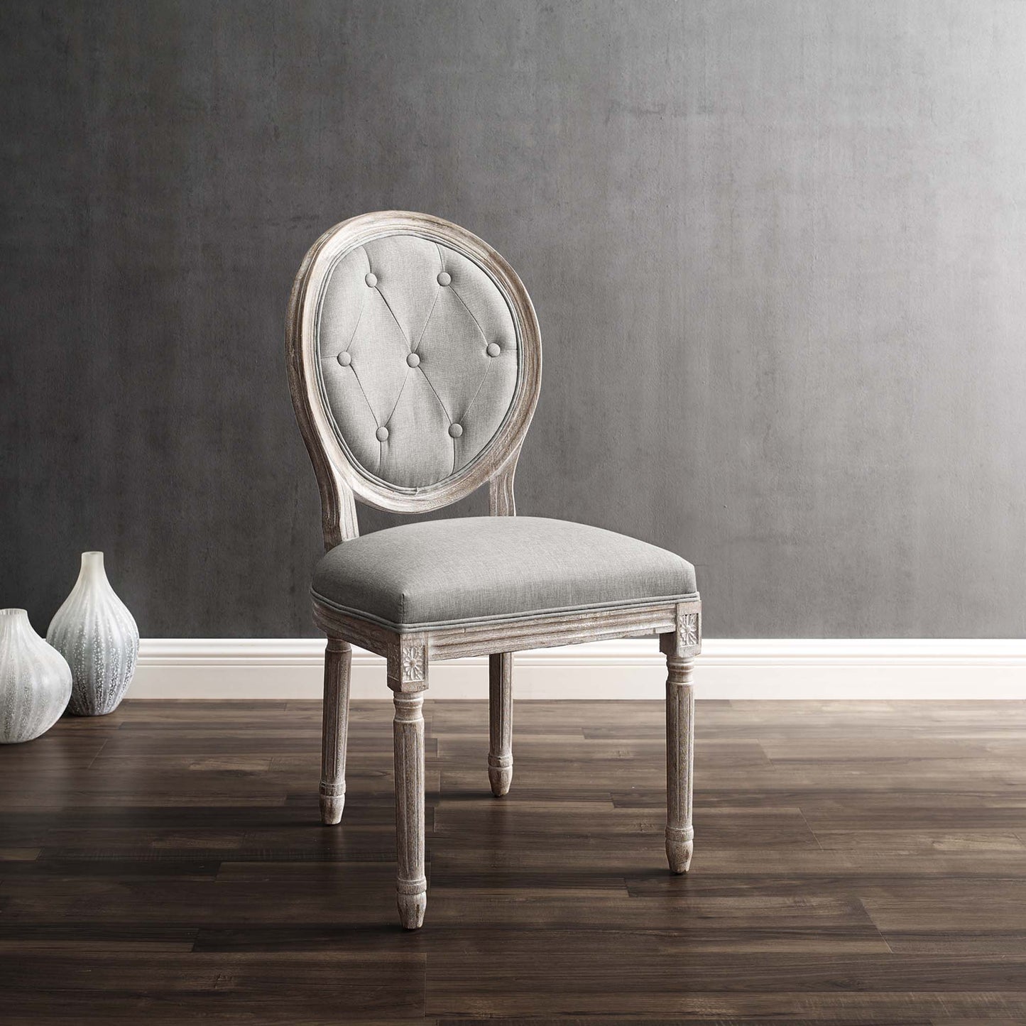 Gray tufted oval-back dining side chair, upholstered in fabric, with a weathered light wood frame and carved legs.