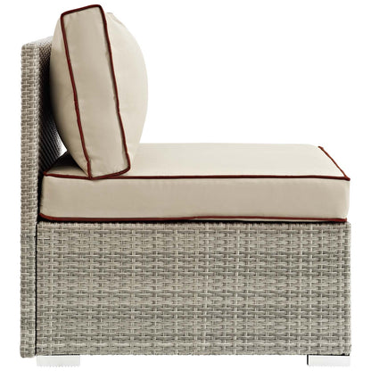 Beige outdoor wicker armless patio chair with burgundy piping and a round bolster pillow.