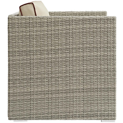 Gray-beige resin wicker outdoor armchair with cream cushion & red piping peeking over the edge