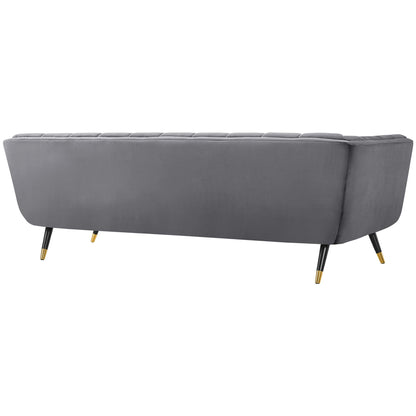 Grey upholstered sofa with tufted back cushions, curved arms, black legs and gold-tipped feet.