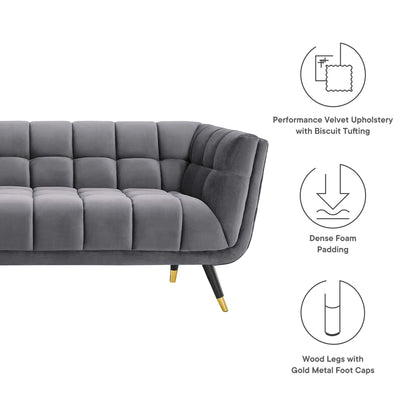 Grey velvet tufted sofa with biscuit tufting, curved silhouette; dense foam padding and wood legs with gold caps.