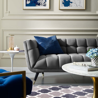Gray tufted mid-century sofa with blue cushion, gold-leg marble coffee table, blue abstract art in a modern living room.
