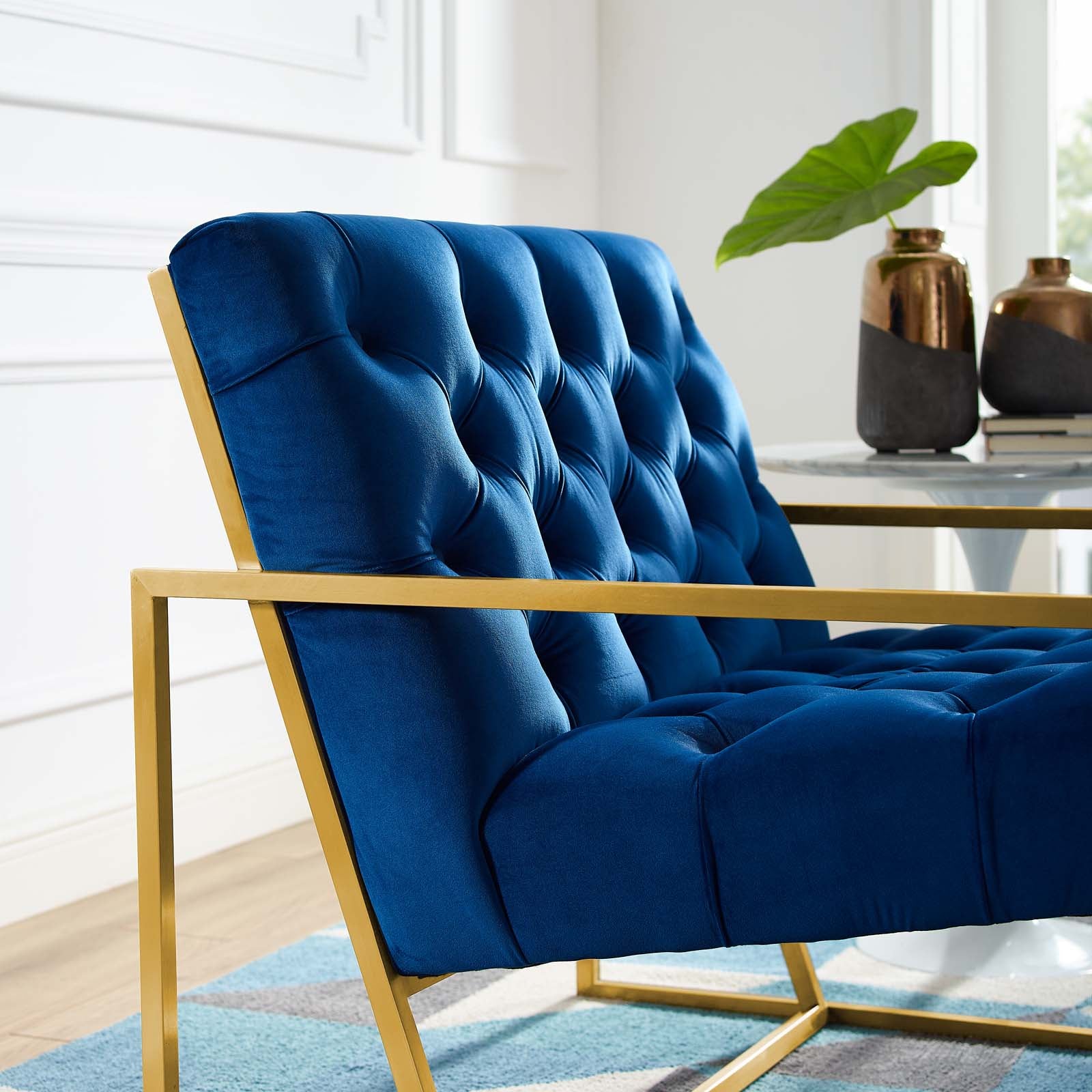 Navy velvet tufted accent chair with a gold-tone stainless steel frame; contemporary living room seating.