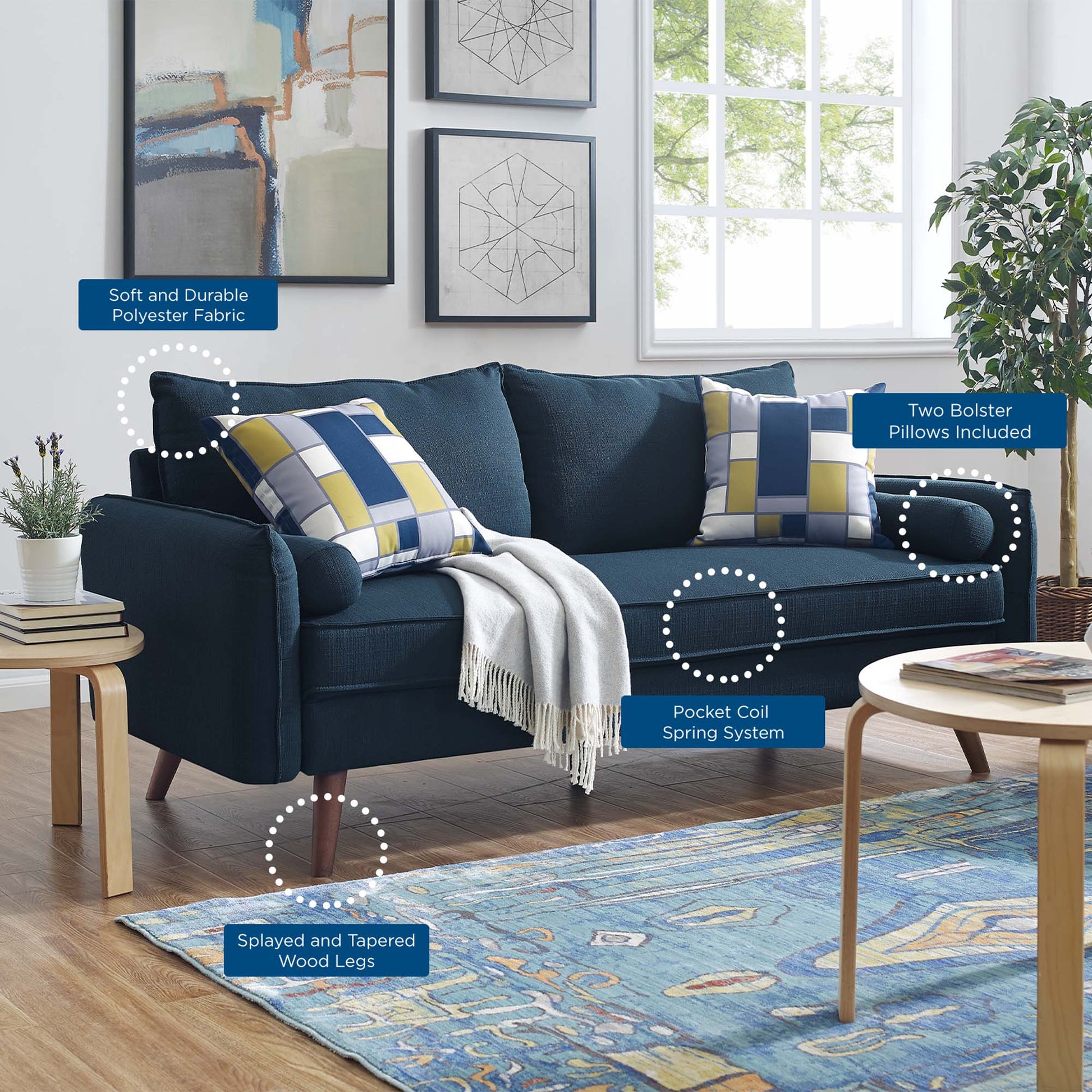 Deep blue fabric sofa with plaid cushions, tapered wood legs, and a light throw; two bolster pillows included; blue area rug.
