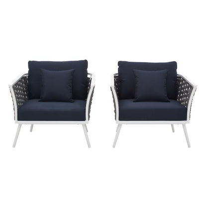 Set of two white outdoor aluminum armchairs with navy cushions and woven dark backs.