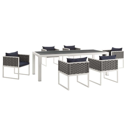 White rectangular outdoor aluminum dining table with a dark top, surrounded by gray aluminum dining chairs with navy cushions.