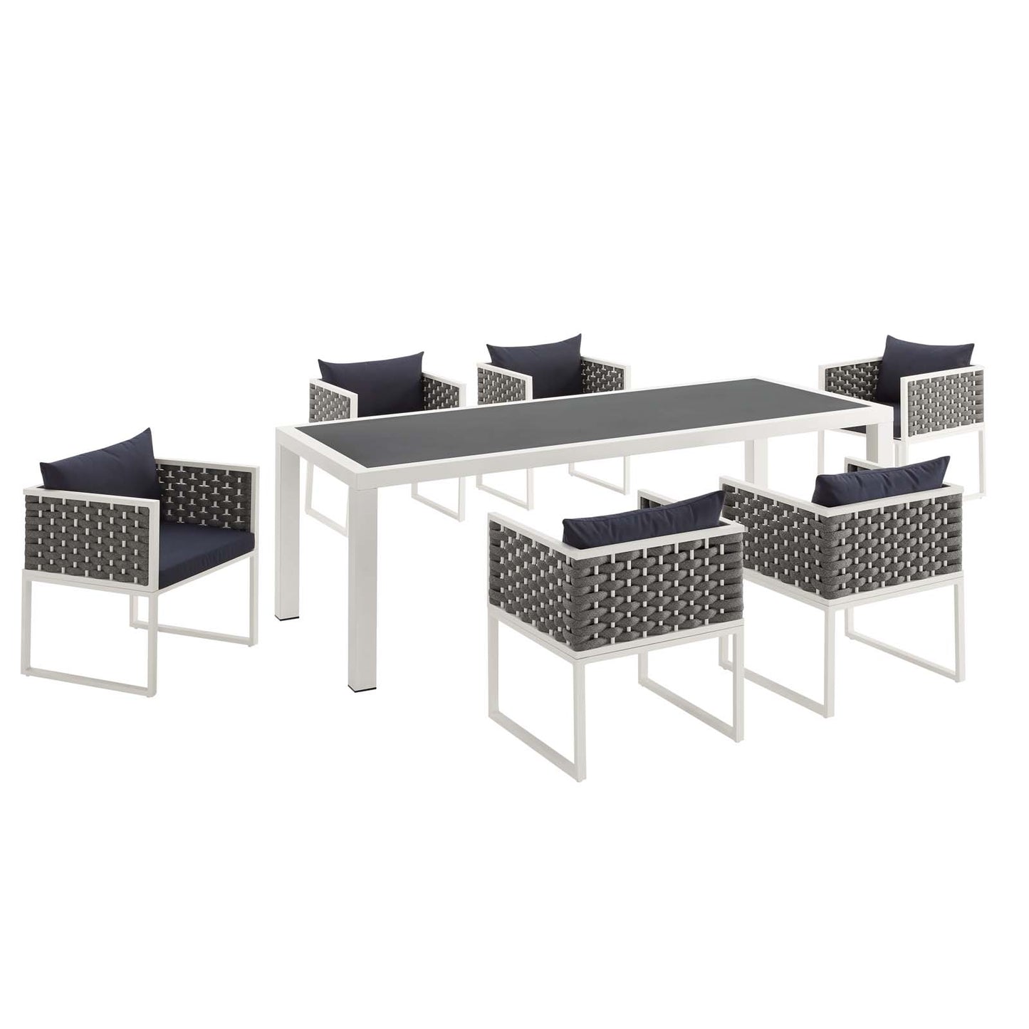White rectangular outdoor dining table with gray woven chairs and navy cushions; 7-piece outdoor dining set.