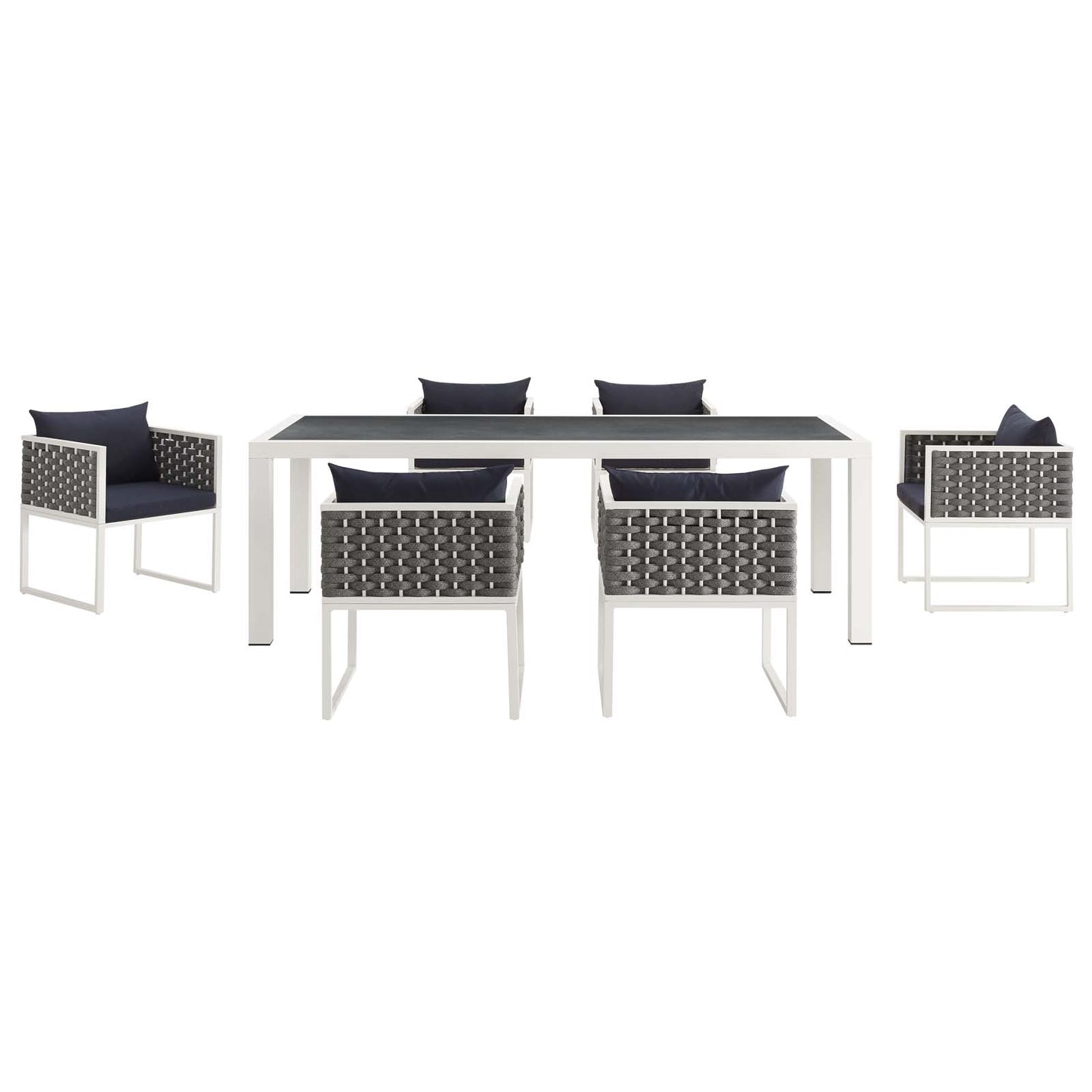 White outdoor dining table with dark top and six gray woven chairs with navy cushions.