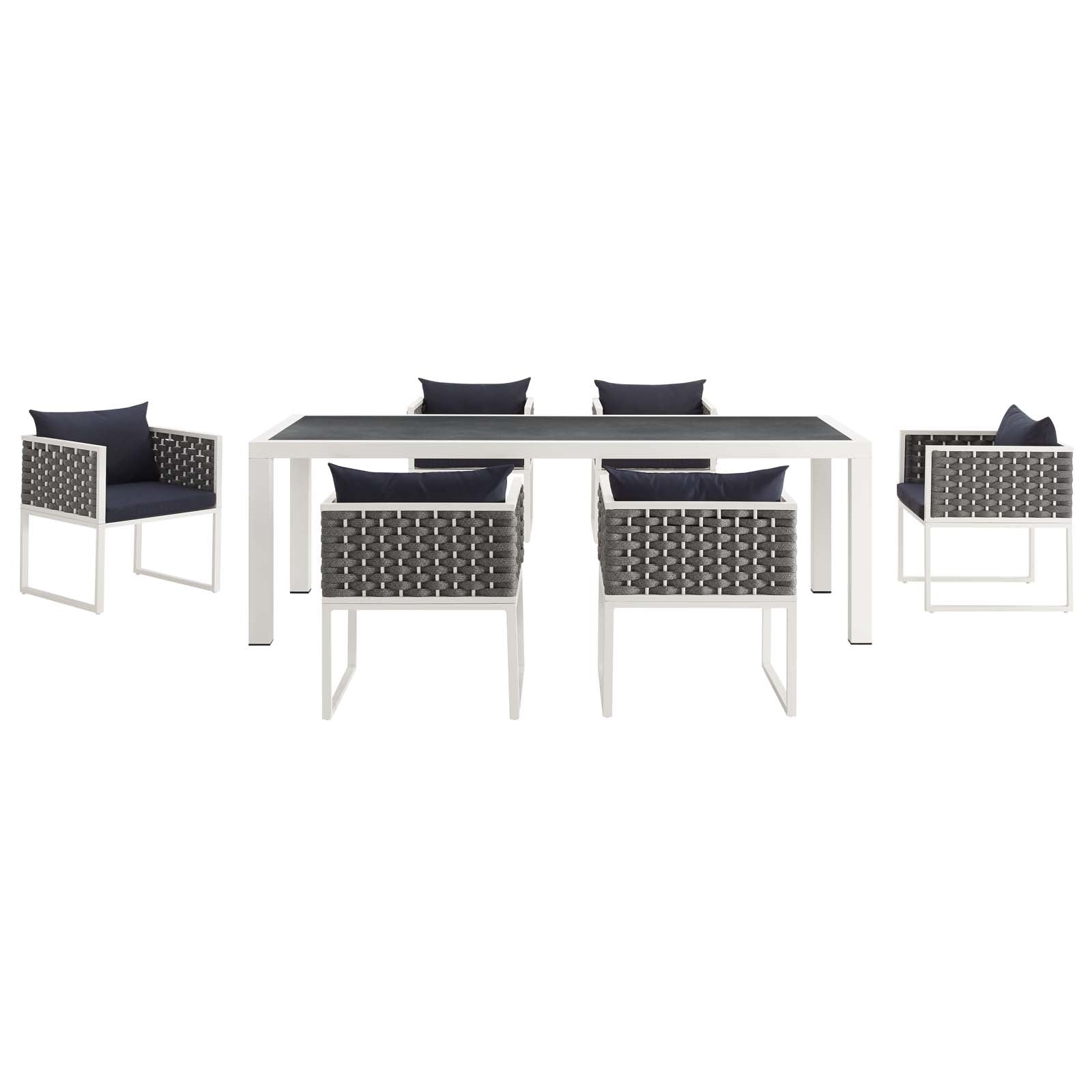White outdoor dining table with dark top and six gray woven chairs with navy cushions.