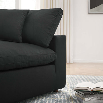 Dark charcoal fabric corner chair with two cushions in a modern living room, rug, curtains, and an open book & magazines nearby.