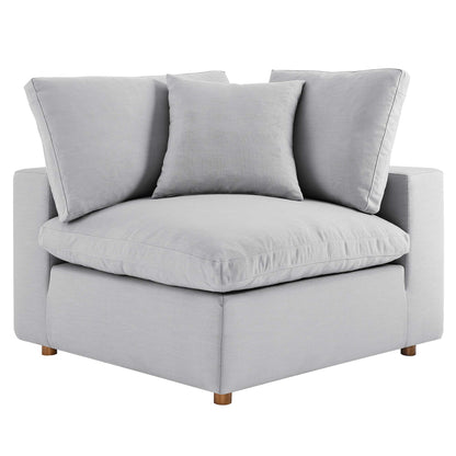 Light gray fabric corner chair with a thick cushioned seat, two large back cushions, and wooden legs.