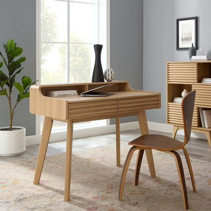 Oak-finish mid-century modern desk with built-in shelf in a bright, cozy home office.