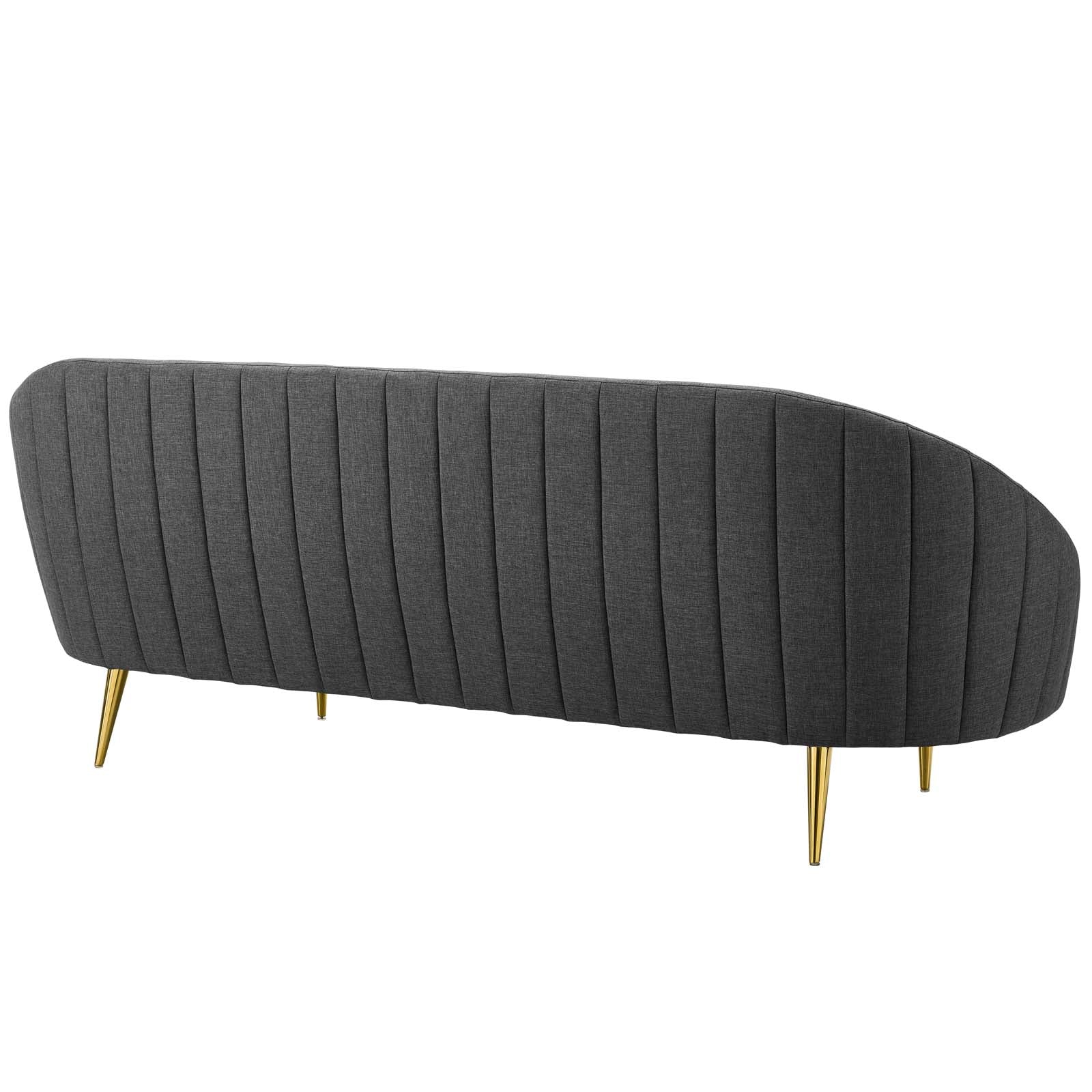 Gray curved sofa with vertical channel tufting and gold tapered legs, mid-century modern style.