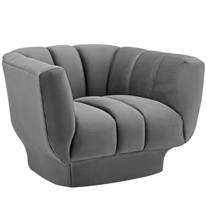 Gray velvet armchair with vertical channel tufting and segmented cushions for a modern, cozy lounge seating.