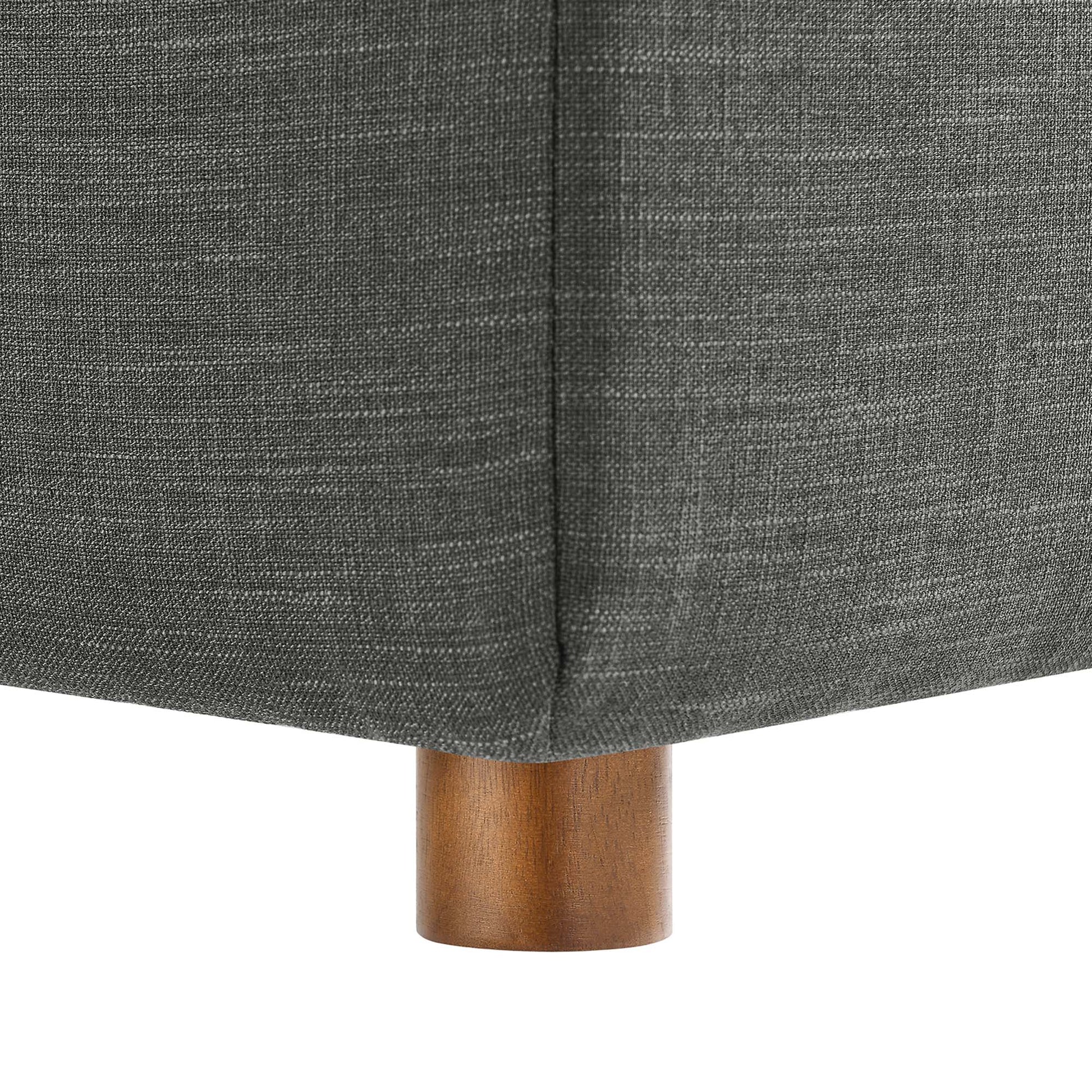 Gray textured sofa upholstery with a corner seam and a short brown wooden leg.