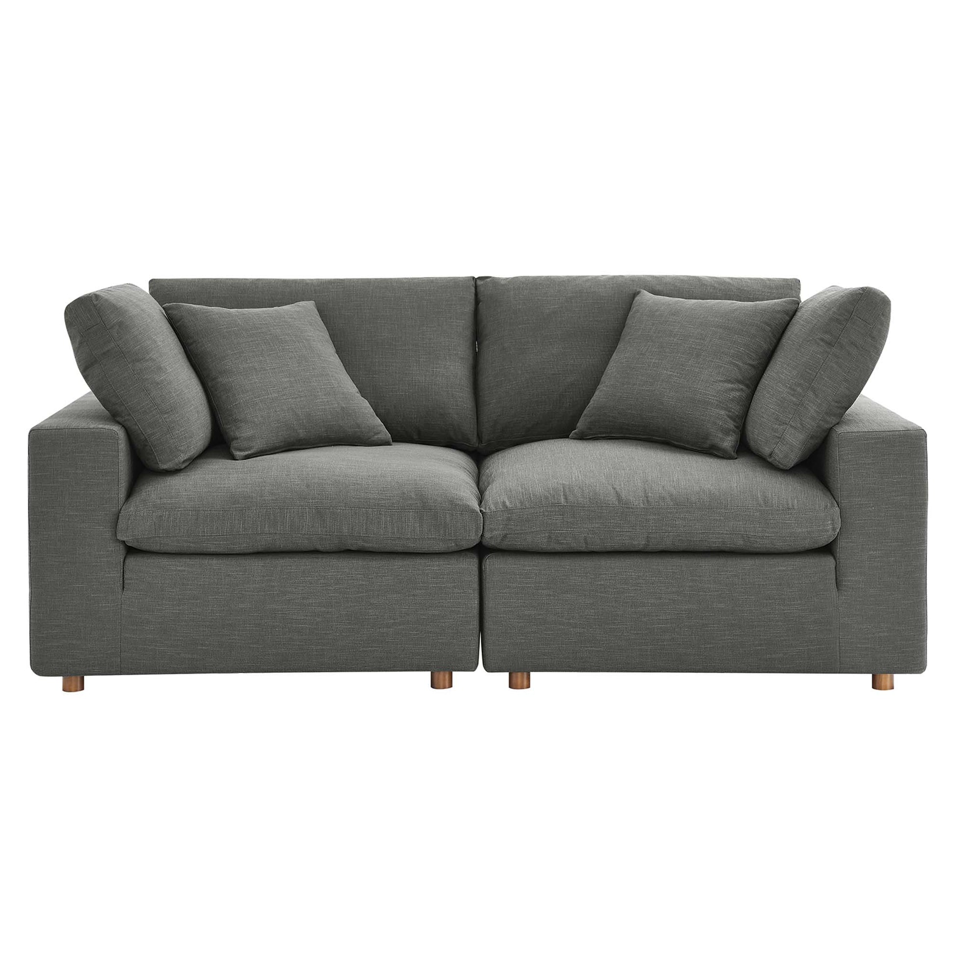 Grey fabric sofa with two-seat sections, multiple cushions and short wooden legs; modern living room centerpiece.