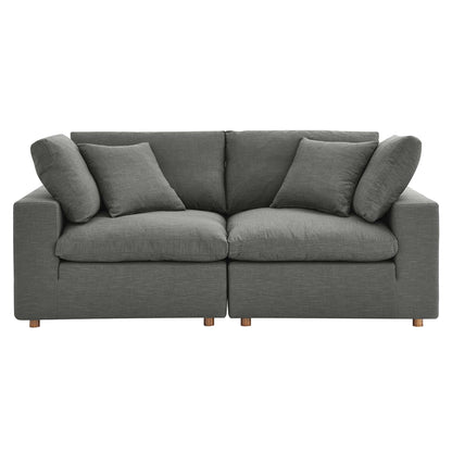 Grey fabric sofa with two-seat sections, multiple cushions and short wooden legs; modern living room centerpiece.