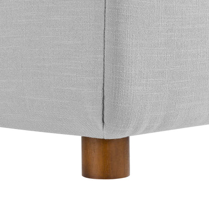 Light gray fabric sectional sofa corner with seam, supported by a short brown wooden leg.