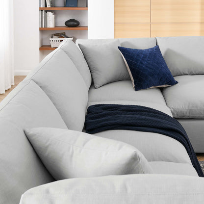 Light gray fabric sectional sofa with a soft navy throw blanket and a blue velvet pillow in a modern living room.