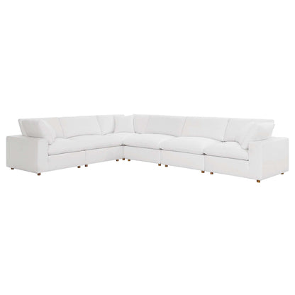 White fabric-covered L-shaped sectional with plush cushions and short wooden legs for a modern living room.