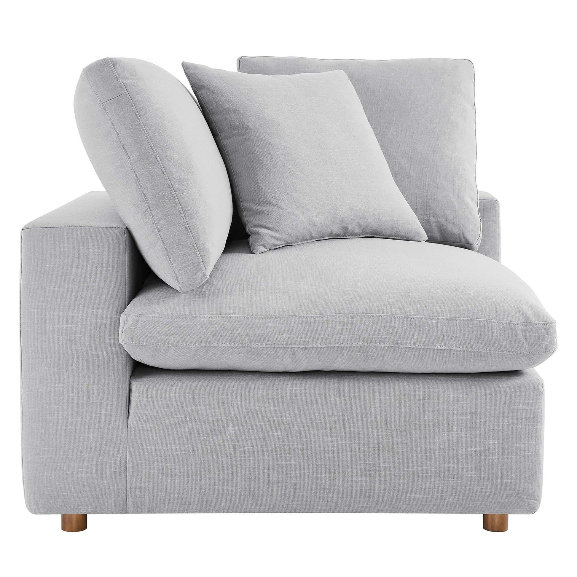 Light gray fabric sectional sofa with low square arms, thick seat cushions, square back cushions and a round bolster, wooden legs.