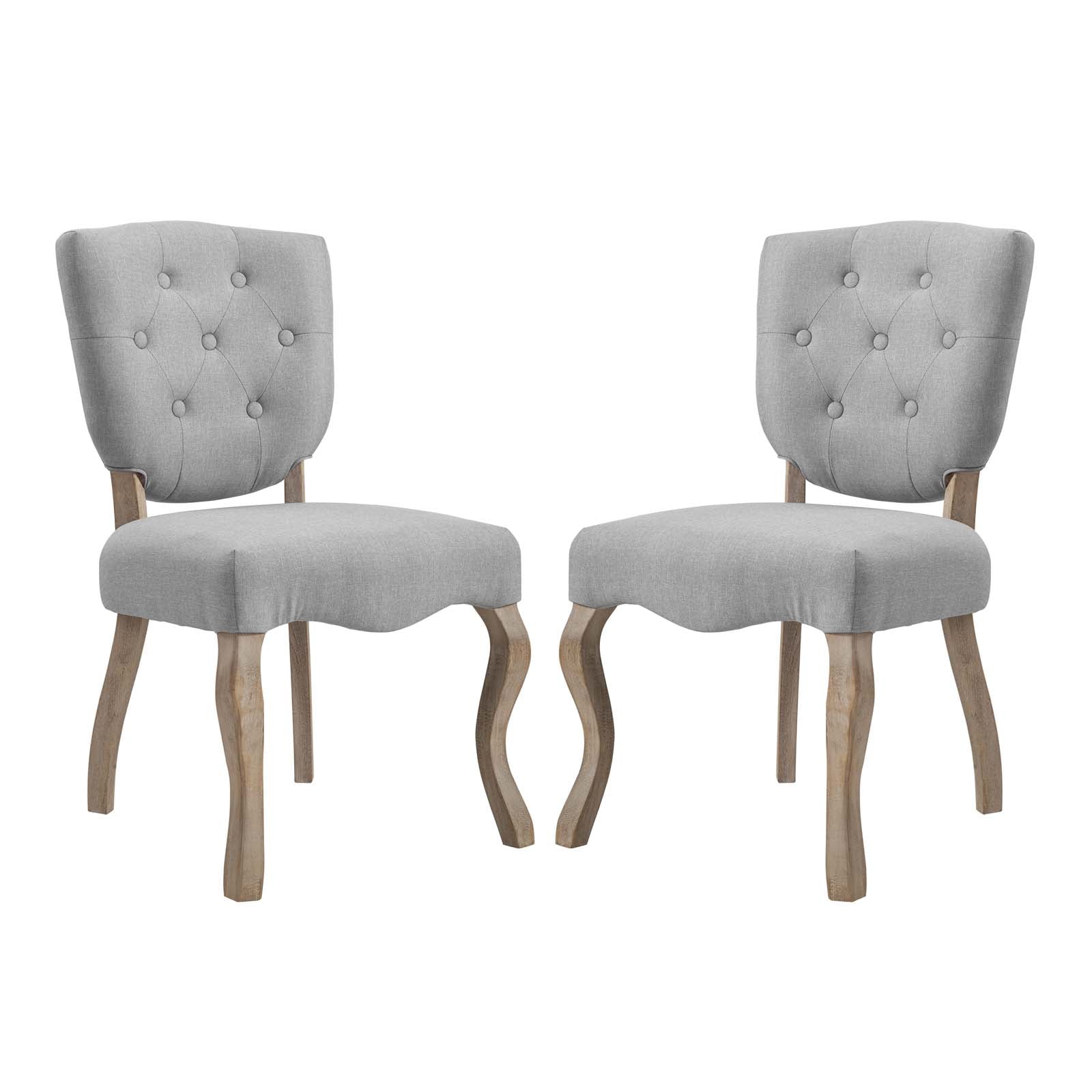 Pair of gray fabric-upholstered dining chairs with tufted backs and curved natural-wood legs.