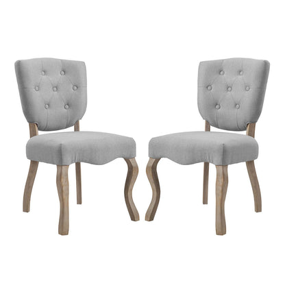 Pair of gray fabric-upholstered dining chairs with tufted backs and curved natural-wood legs.