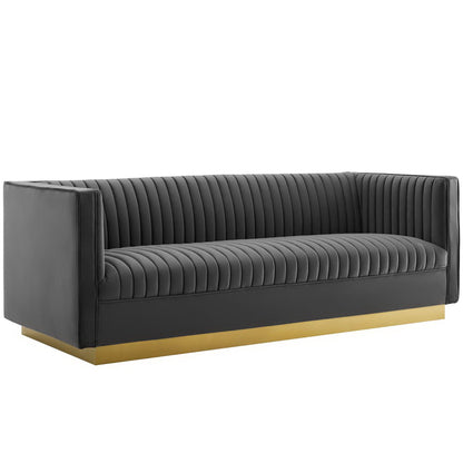 Gray velvet sofa with vertical channel tufting, square arms, low back, & gold metal base.
