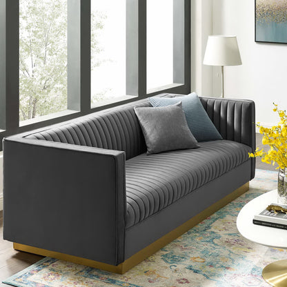Gray vertical-channel tufted velvet sofa with a wooden base in a modern living room.