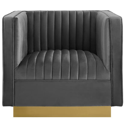 Dark gray velvet armchair with vertical channel tufting, square arms, and a gold-tone metal base.