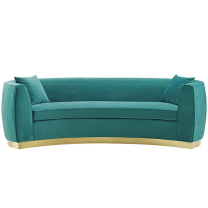 Blue velvet curved sofa with rounded arms, two cushions, and a gold-tone curved base.