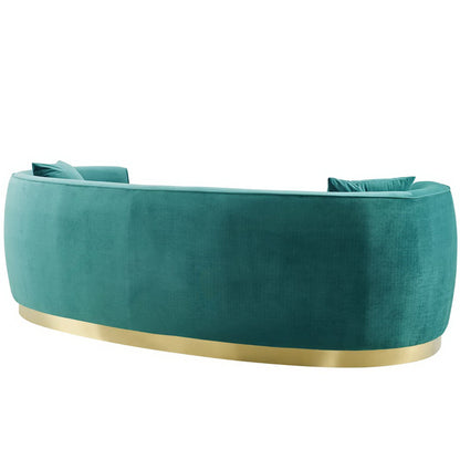 Blue curved velvet sofa with a metal base and matching cushions, modern lounge piece.