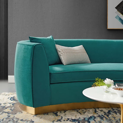 Blue curved velvet sofa with rounded arms and a gold base, white textured cushion, in a modern living room.