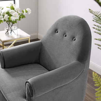 Grey velvet upholstered accent chair with rounded back and armrests, tufted button detailing, in a modern living room.