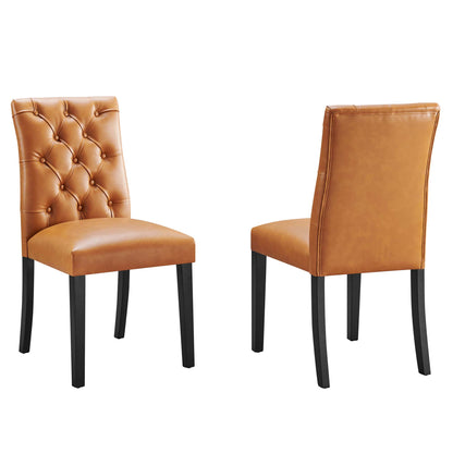 Two tan vinyl dining chairs; left chair with a tufted diamond back, right chair with a plain back, dark wood legs.