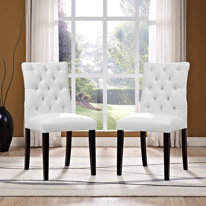 Pair of white vinyl dining chairs with dark wood legs, modern style.